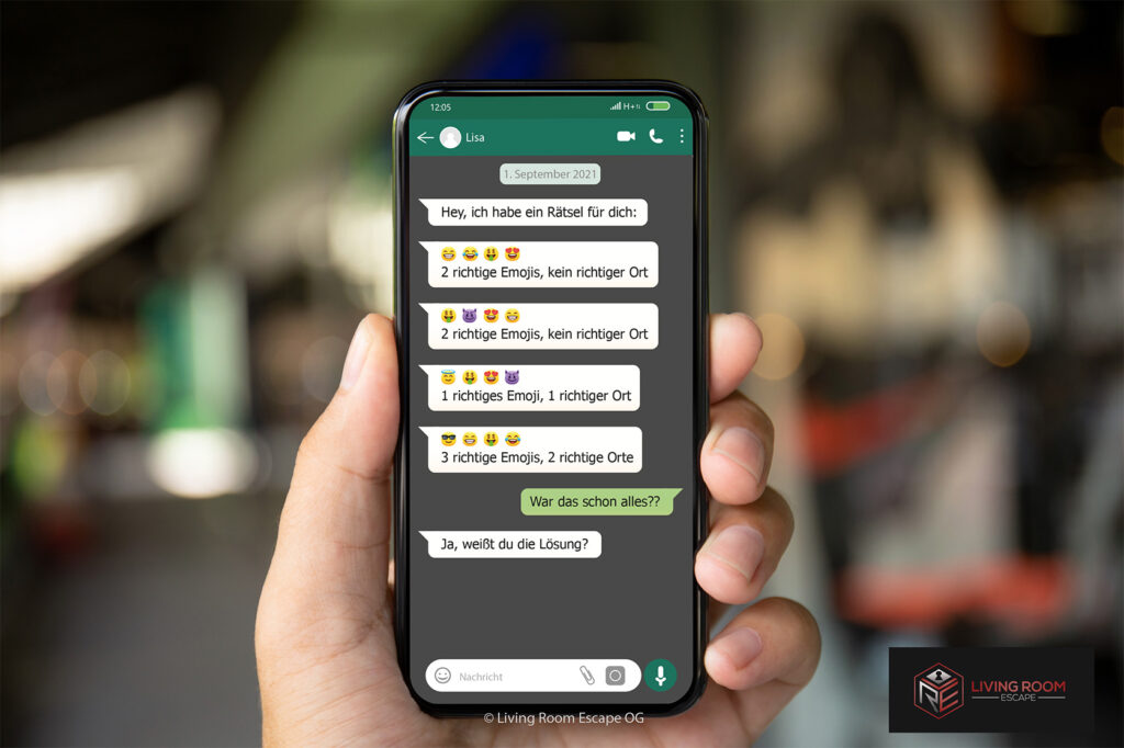 Hand, die ein Smartphone mit Chatverlauf über ein Rätsel mit Emojis hält.